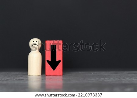 Wooden doll and downward arrow with copy space. Demote, low morale and feeling down concept Royalty-Free Stock Photo #2210973337