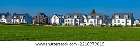 Semi-detached houses with gardens in a new development area on the edge of a field in beautiful summer weather and blue, cloudless sky Royalty-Free Stock Photo #2210979015