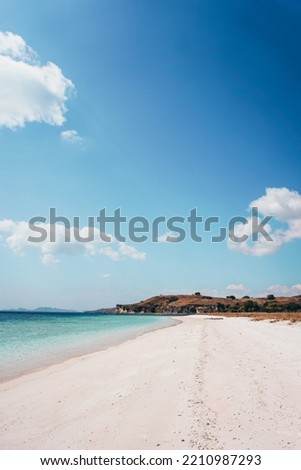Tropical white sandy beach with hill and clear water of Labuan Bajo, Indonesia