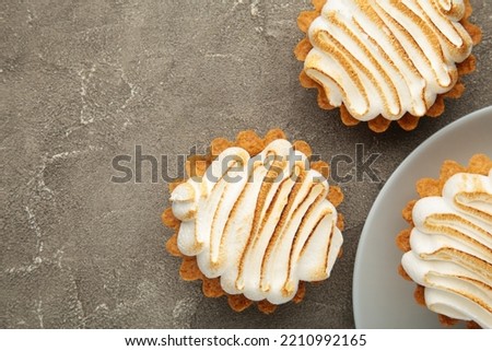 Appetizing lemon cupcakes with white cream on grey background. Holiday, surprise, birthday, Valentine's Day. Top view.