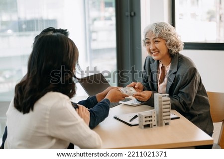 Happy couple in love buying house, renting apartment, getting mortgage. Married woman and man meeting with real estate agent, broker, signing agreement for sale and purchase
