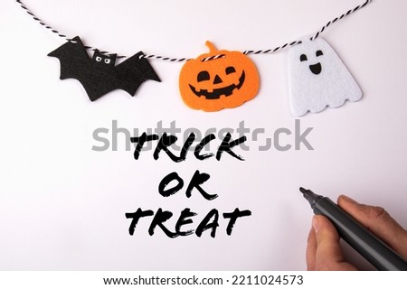 Trick or treat. Hand with a black marker on a white background. Halloween decorations.