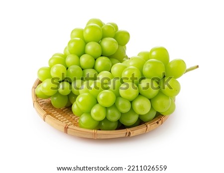 Shine Muscat in a bamboo colander on a white background. White grapes. Japanese grapes. Royalty-Free Stock Photo #2211026559