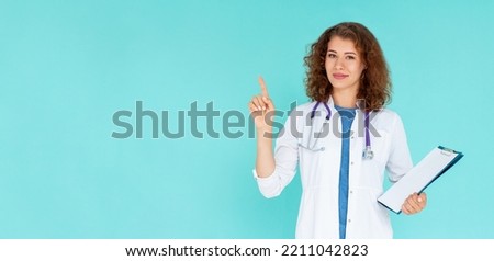 Portrait of young female doctor showing something or copyspase for product or sign text, with blue folder, over blue background
