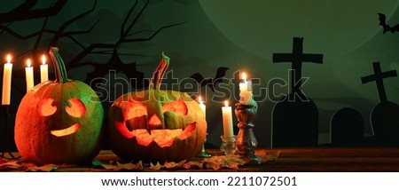 Carved Halloween pumpkins with burning candles and autumn leaves on table at cemetery