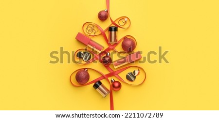 Creative Christmas tree made of makeup cosmetics, jewelry and ribbon on yellow background