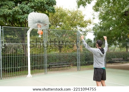 Unrecognizable sportive man celebrating scoring a basketball basket in an outdoor court