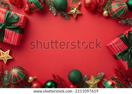 Christmas Eve concept. Top view photo of present boxes with bows red green baubles gold star ornaments mistletoe and pine branches in snow on isolated red background with blank space in the middle