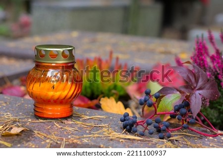An orange candle on a grave in a cemetery on an autumn day. All Saints Day. Copy space, shallow depth of field. Royalty-Free Stock Photo #2211100937