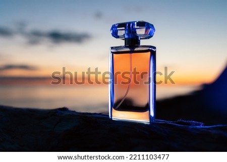 Selective perfumes. Close up of glass transparent perfume bottle on the background of a twilight sunset. Copy space. Presentation of luxurious evening toilet water. Royalty-Free Stock Photo #2211103477
