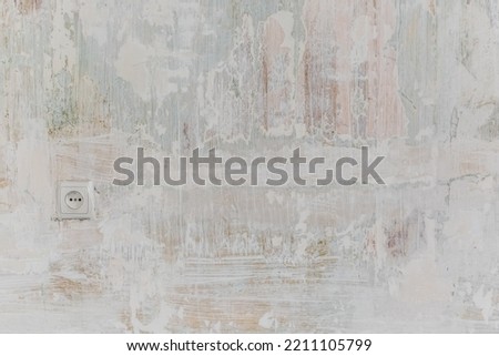 Primed wall with European electrical outlet. Surface painted with white paint. Abstract vintage texture of a shabby wall during renovation. Background with copy space