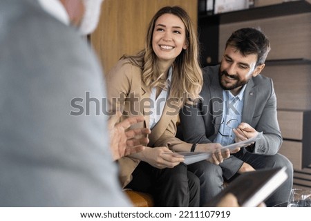 Young couple looking to buy a new car. Car salesman making a sale. Signing a papers for purchase a new car