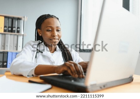 healthcare, medical and technology concept - african female doctor with laptop. Royalty-Free Stock Photo #2211115399