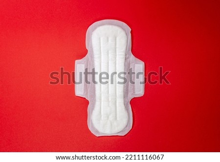A sanitary pad lies on a red background. Menstrual cycle and pregnancy. Negative pregnancy test and contraceptives. Sanitary napkin Royalty-Free Stock Photo #2211116067