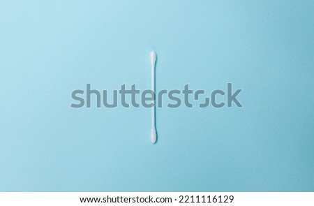 A white cotton swab on a light blue background. Ear stick and cotton swab for cosmetology and hygiene. White cotton buds Royalty-Free Stock Photo #2211116129