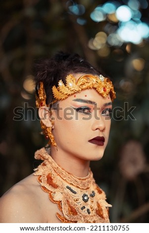 Portrait of Thailand man wearing a golden necklace and golden crown while shirtless inside the jungle lonely by himself