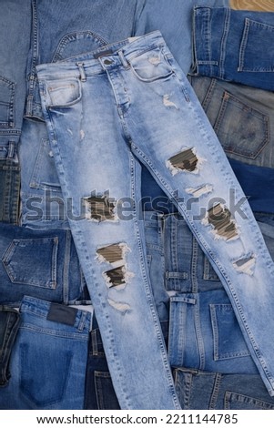Lots of blue ,torn jeans pants in a stack. Denim background.