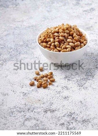 Fried soybeans or "kacang kedelai goreng" in a bowl on a white background. with the concept of minimalist photography