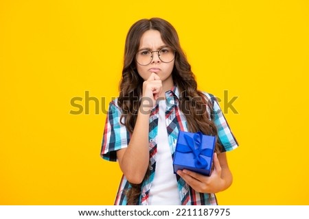 Teenager kid with present box. Teen girl giving birthday gift. Present, greeting and gifting concept. Thinking pensive clever teenager girl.