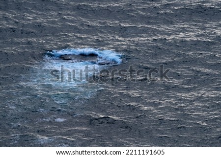 big dark stone in the Atlantic Ocean washed over by crashing waves