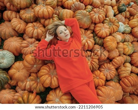 Young beautiful woman near orange pumpkins