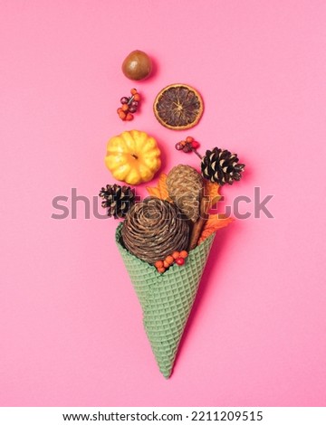 Green ice cream cone made of autumn taste on vibrant pink background. Creative fall season decorated with pine cone, pumpkin, leaf, orange. Minimal thanksgiving table decoration with natural fall.