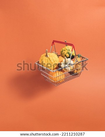 Shopping basket full of pumpkin lands on orange background. Minimal colorful autumn concept. Creative fall idea perfect design for thanksgiving. Shopping colorful nature fall season.