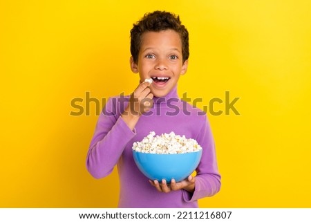 Photo of excited funky person arms hold eat popcorn plate have good mood isolated on yellow color background
