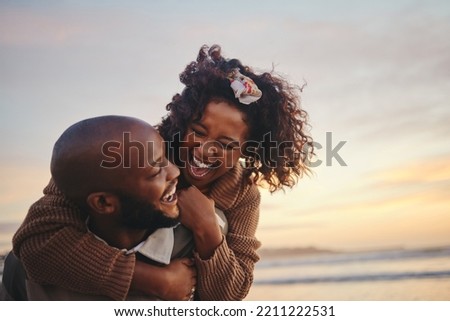 Love, travel and fun couple at beach enjoying summer vacation or honeymoon at sunset with a piggy back ride while being playful. Laughing, energy and seaside holiday with black man and woman together