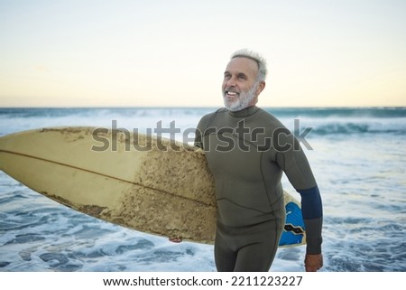 Water, happy and man surfing at the beach on a tropical holiday in Hawaii during sunrise in summer. Mature surfer with smile for the waves in ocean on vacation on an island for travel and adventure Royalty-Free Stock Photo #2211223227