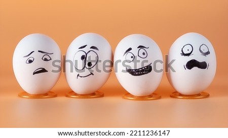 Four eggs with painted funny faces representing people in different emotional states. Close up view on beige background