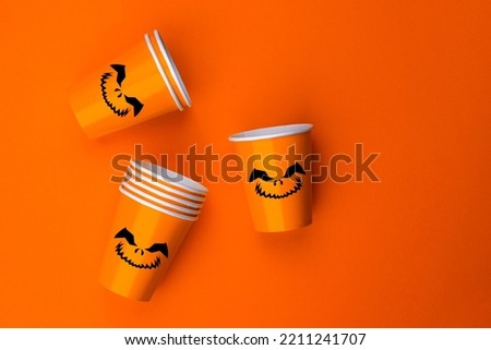 Halloween party background with Paper cup with Jack lantern face decoration. Disposable cup made of recycled paper orange colors. Pattern for outumn october holiday all saints day celebration.