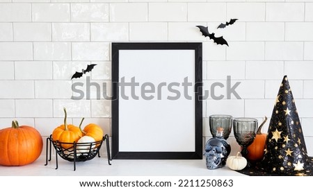 Happy Halloween holiday concept. Picture frame mockup with witch hat, pumpkins, skull, wine glasses, bats on table in nordic home interior