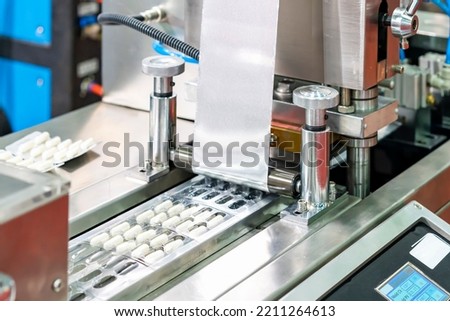 capsules wrapped in ptp sheet during manufacturing process by machine blister packing machine for pharmaceutical in industrial Royalty-Free Stock Photo #2211264613