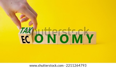 Taxonomy and economy symbol. Businessman hand Turnes cubes and changes word Economy to Taxonomy. Beautiful yellow background. Business and Taxonomy and economy concept. Copy space