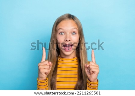 Photo of charming astonished girl open mouth indicate fingers up empty space isolated on blue color background