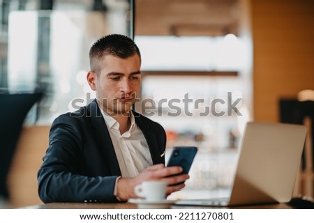 Happy business man sitting at cafeteria with laptop and smartphone