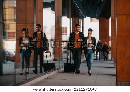 Business man and business woman talking and holding luggage traveling on a business trip, carrying fresh coffee in their hands.Business concept Royalty-Free Stock Photo #2211271047