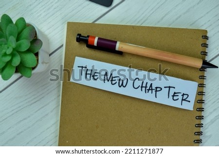 Concept of The New Chapter write on sticky notes isolated on Wooden Table.