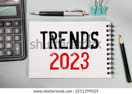 Text TRENDS 2023 on white paper between white and brown spiral notepads.