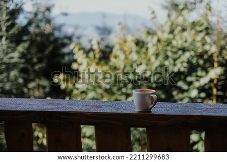 A handmade cup standing on a wood fence. Beautiful scene with a handmade cup standing on a wood fence with mountains view in the background at sunset. Carpathians, Ukraine.