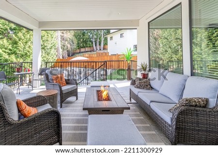 A luxurious spacious deck with stylish patio furniture with a fire pit table heater Royalty-Free Stock Photo #2211300929