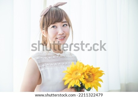 smiling asian woman holding sunflower