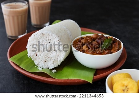Popular South Indian breakfast puttu pittu made of rice flour and coconut with banana and kadala curry in Kerala breakfast India. Bamboo puttu prepared in steam