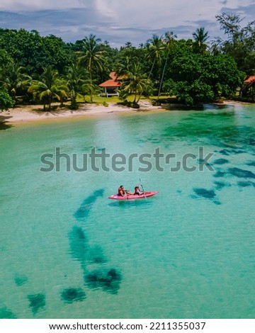 Men and women in Kayak in the ocean of the tropical Island of Koh Mak Thailand. men and women in kayaks at a blue ocean and white beach with palm trees Royalty-Free Stock Photo #2211355037