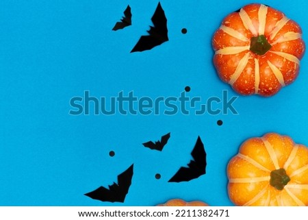 Halloween decorations concept, Scary smile pumpkin and flying black bat on light blue background.