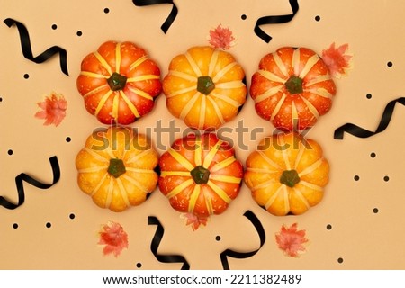 Halloween symbol concept, Scary smile pumpkins with maple leaves are arranged on cream background.