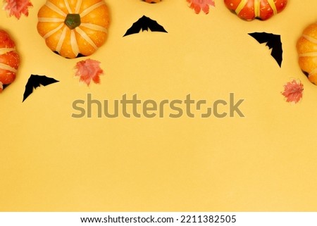 Halloween symbol concept, Scary smile pumpkin and black bat with maple leaves on yellow background.