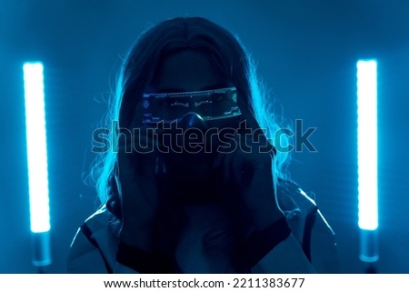 Futuristic, silhouette of a young woman from the future, with luminous augmented reality glasses looking at the camera