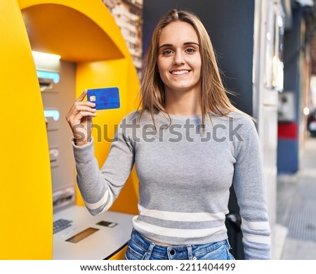 Young doctor woman holding credit card at cash point looking positive and happy standing and smiling with a confident smile showing teeth 